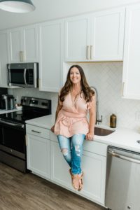 woman in pink top poses by kitchen during branding photos in Nashville TN