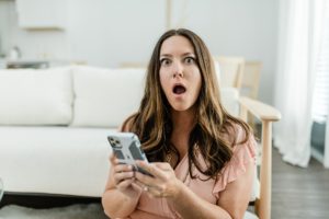 woman makes funny face during branding photos while looking at phone