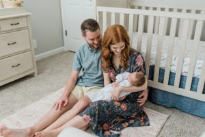 parents look at daughter by crib during newborn photos