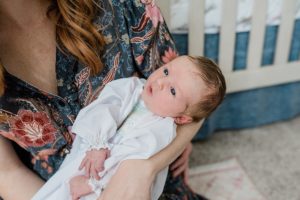 mom holds baby girl during newborn photos at home