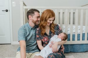 parents look at baby girl during newborn photos at home