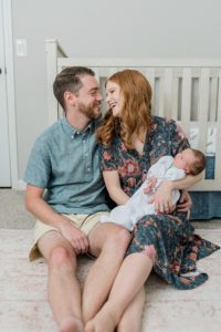 parents sit by crib during newborn photos at home