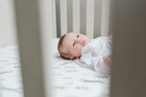 baby lays in crib during newborn photos at home