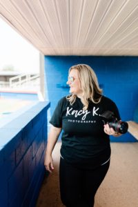 senior portrait photographer poses in dug out at softball field