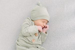 baby lays on crib in sage green wrap