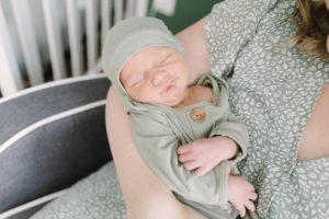 baby sleeps in sage green wrap during Lifestyle Newborn Session in Nashville