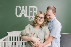 new parents hold baby in bed during newborn photos