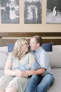 new parents hold baby in bed during newborn photos