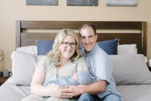 new family of three sits on bed during family photos in Nashville