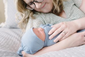 mom looks down at baby boy during newborn photos at home