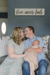 parents touch noses sitting on couch during Lifestyle Newborn Session in Nashville