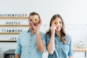 husband and wife stand with bagels to their eyes