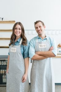 husband and wife stand back to back in kitchen during Nashville branding photography session