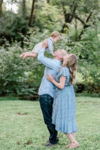 dad lifts toddler in the air during family photos