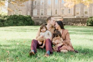 dad kisses mom's forehead while holding toddlers at Cheekwood Estate
