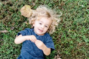 toddler lays in the grass during family portraits