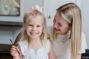 mom smiles at daughter during branding photos at home
