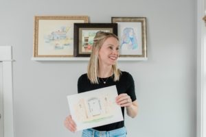 woman holds watercolor paintings during Nashville branding session at home
