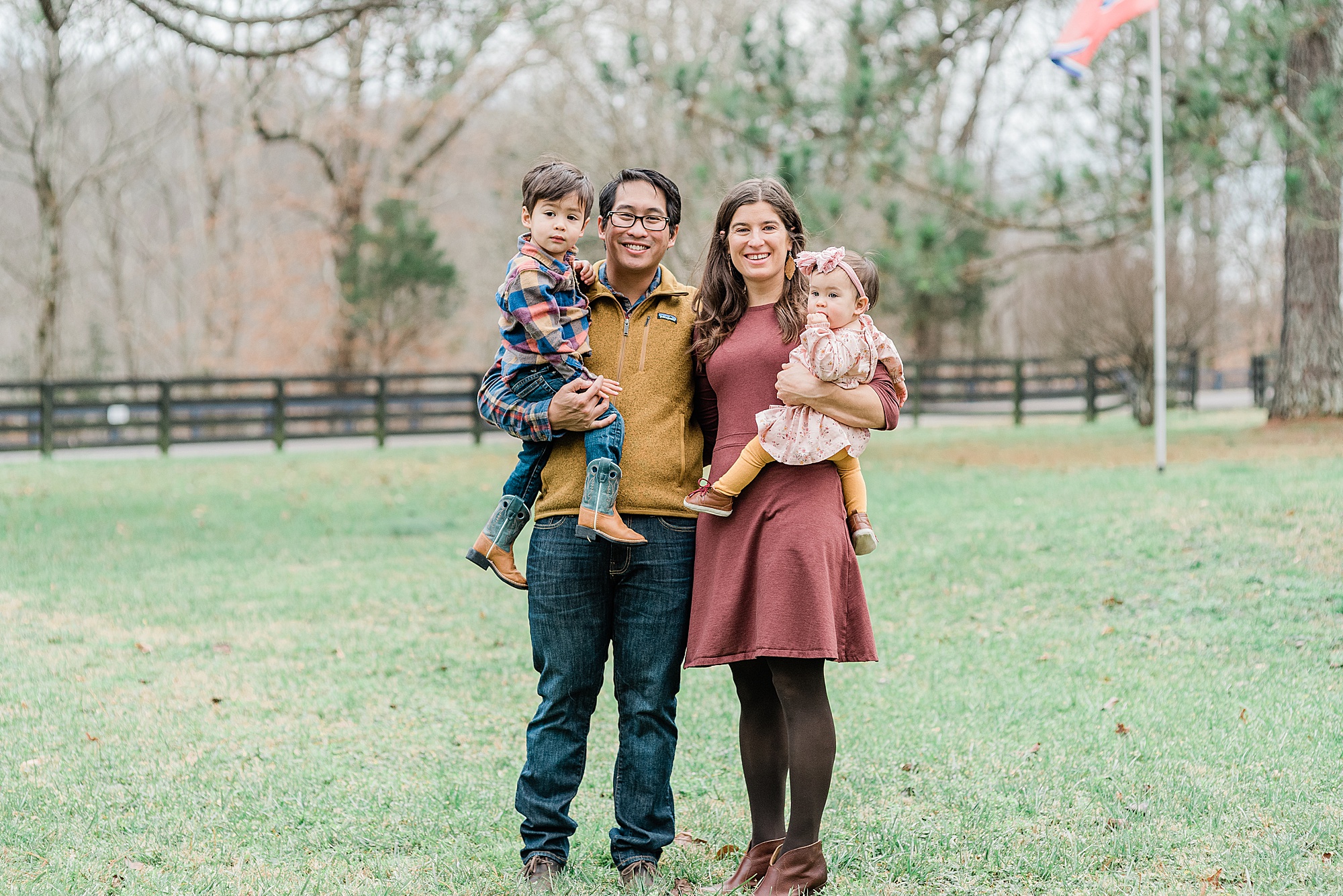 family of four hugs in field during Nashville family photos
