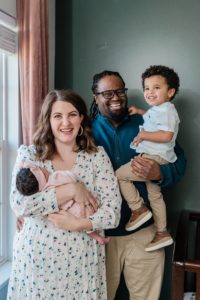 family of four poses by window during Nashville lifestyle newborn session