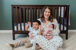 mom sits with baby girl and toddler son during newborn photos