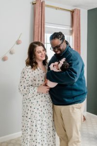 parents look at daughter standing in nursery during Nashville lifestyle newborn session