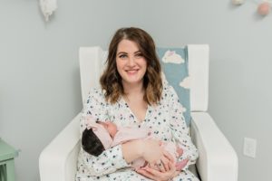 mom holds baby girl during newborn photos at home