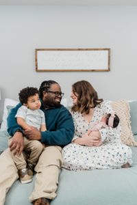 parents smile together holding two kids during Nashville lifestyle newborn session