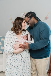 parents hold daughter while leaning heads together during Nashville lifestyle newborn session