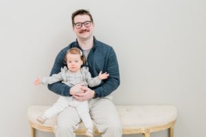 dad sits on bench with daughter during studio family photos