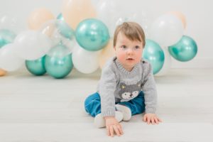 one year old sits in front of balloon garland during Nashville studio family portraits