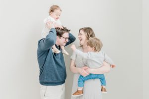 parents laugh with kids in their arms during studio family photos in Nashville TN