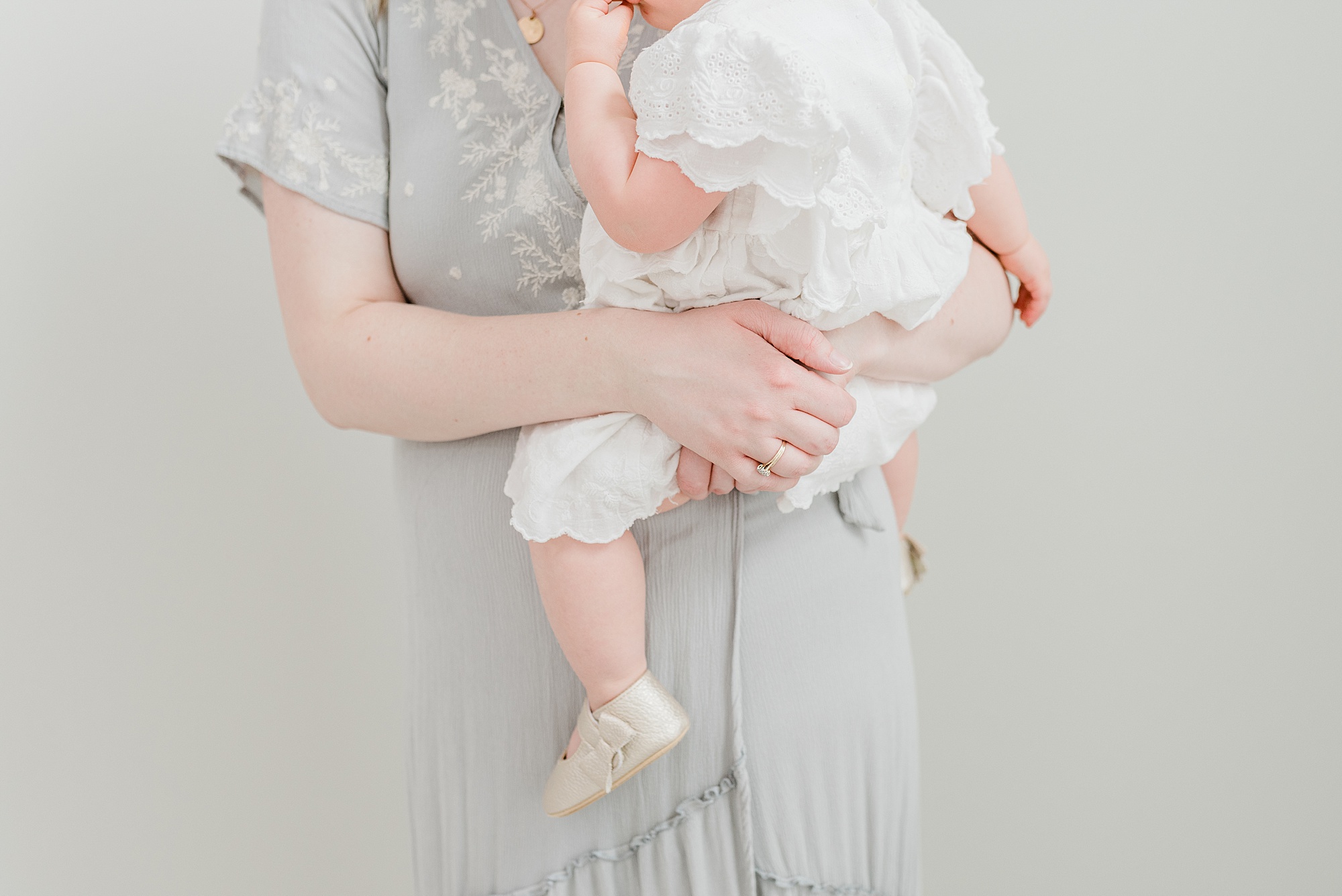 mom hugs daughter in white onesie during Nashville studio family portraits