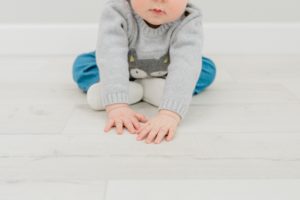 baby leans on studio floor during milestone photos
