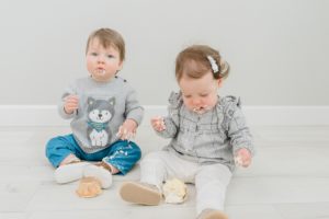 twins play with cupcakes during milestone photos in studio