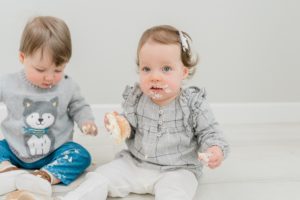 girl holds cupcake piece during first birthday milestone photos