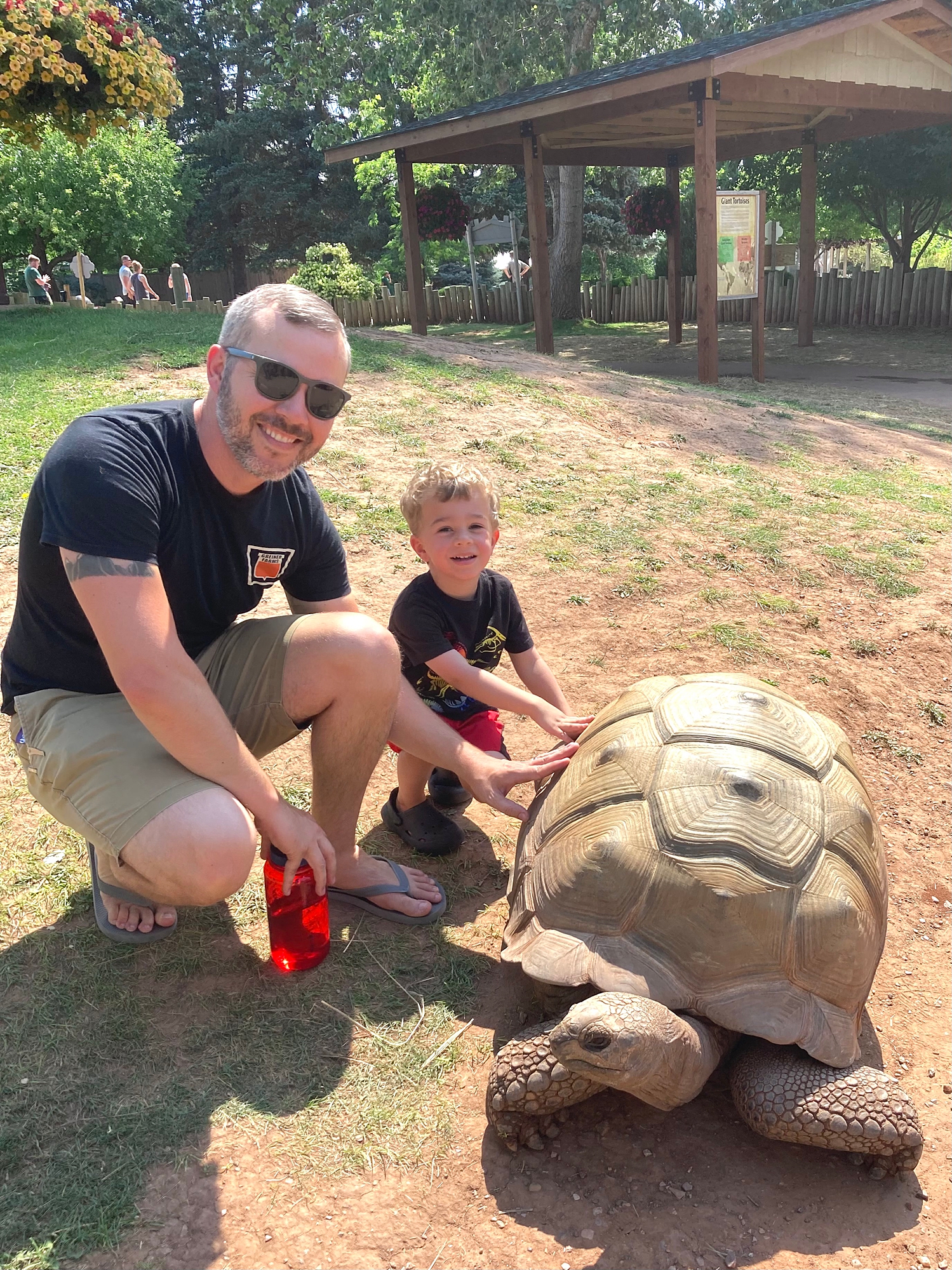 father_and_son_posing_in_front_of_a_big_turtle