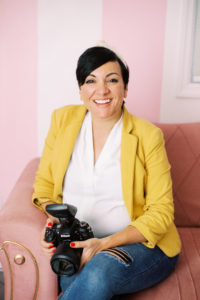 dolly_delong_photography_is_sitting_on_a_pink_couch_at_nashville_pinky_house_for_headshots_wearing_a_yellow_cardigan