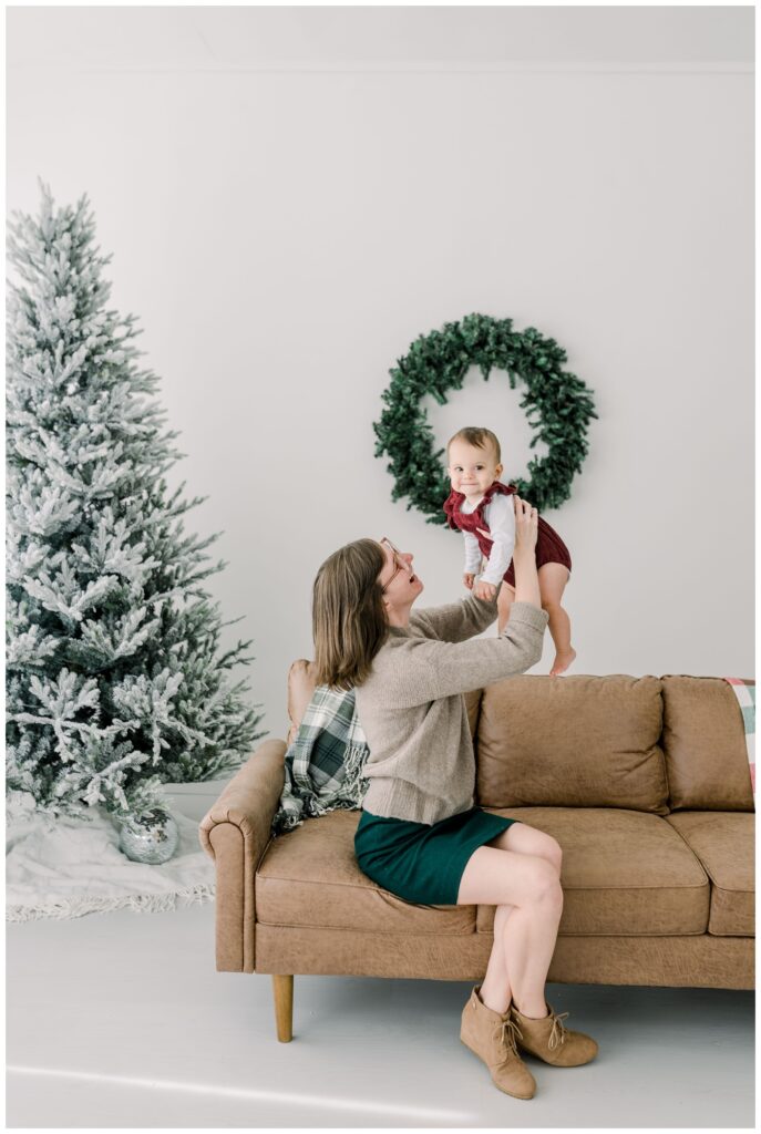 Mommy_is_holding_her_baby_girl_up_in_the_air_for_christmas_photos_at_Vow_Collective_Studio_by_Nashville_Family_Photographer_Dolly_DeLong