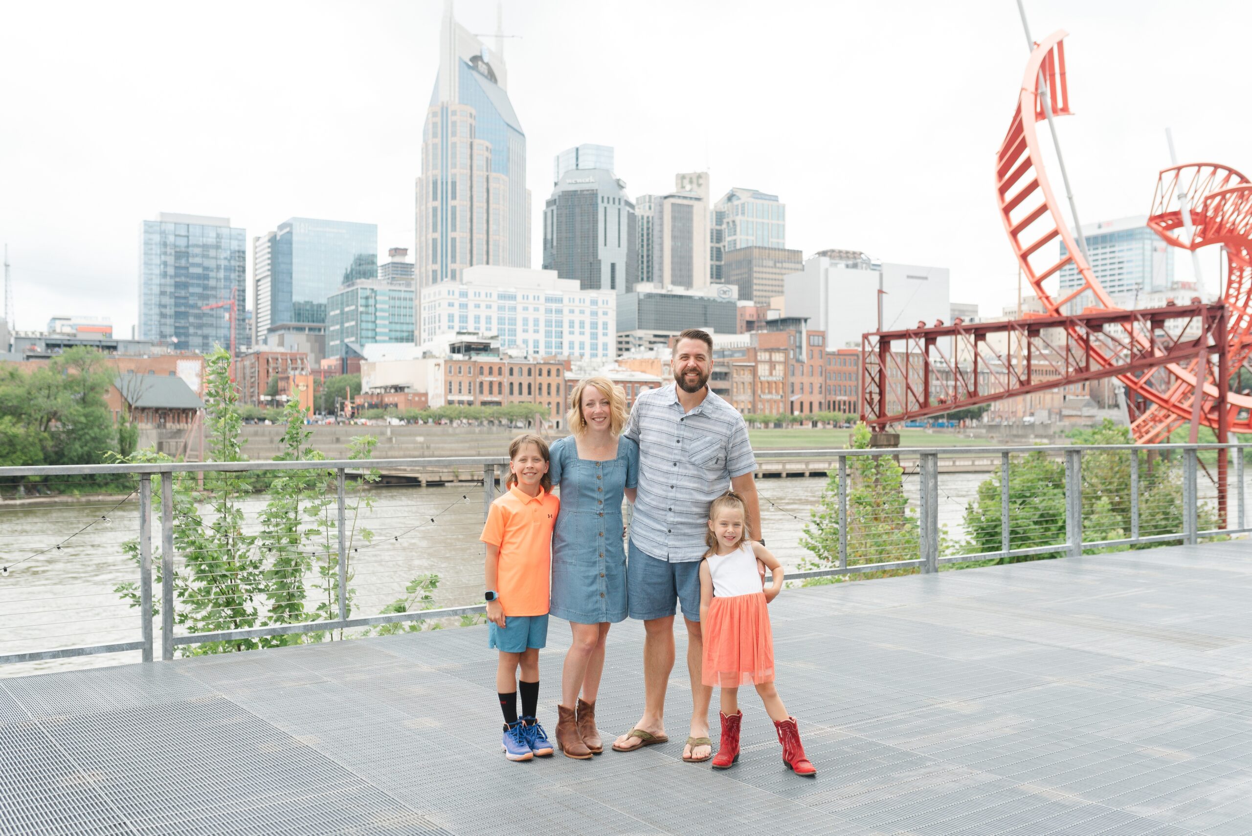 a_family_of_four_poses_for_their_family_photos_in_downtown_Nashville_near_the_skyline_and_batman_building_by_Nashville_Family_Photographer_Dolly_DeLong