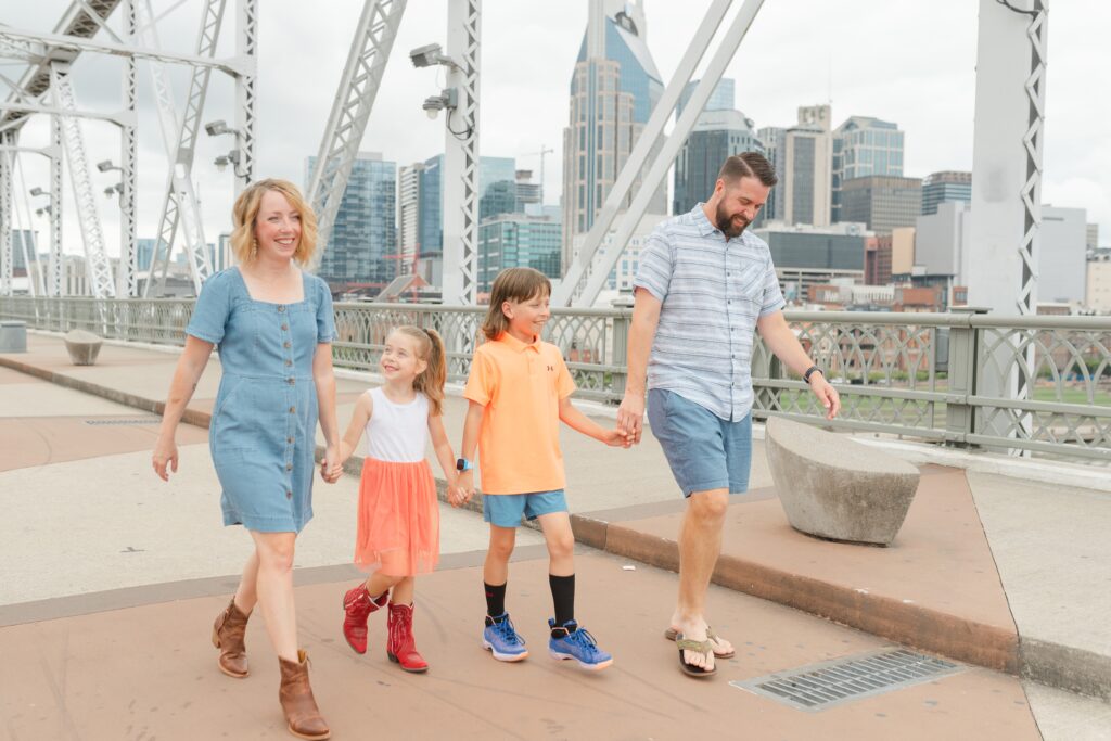 a_family_of_four_poses_for_their_family_photos_in_downtown_Nashville_near_the_skyline_and_batman_building_by_Nashville_Family_Photographer_Dolly_DeLong