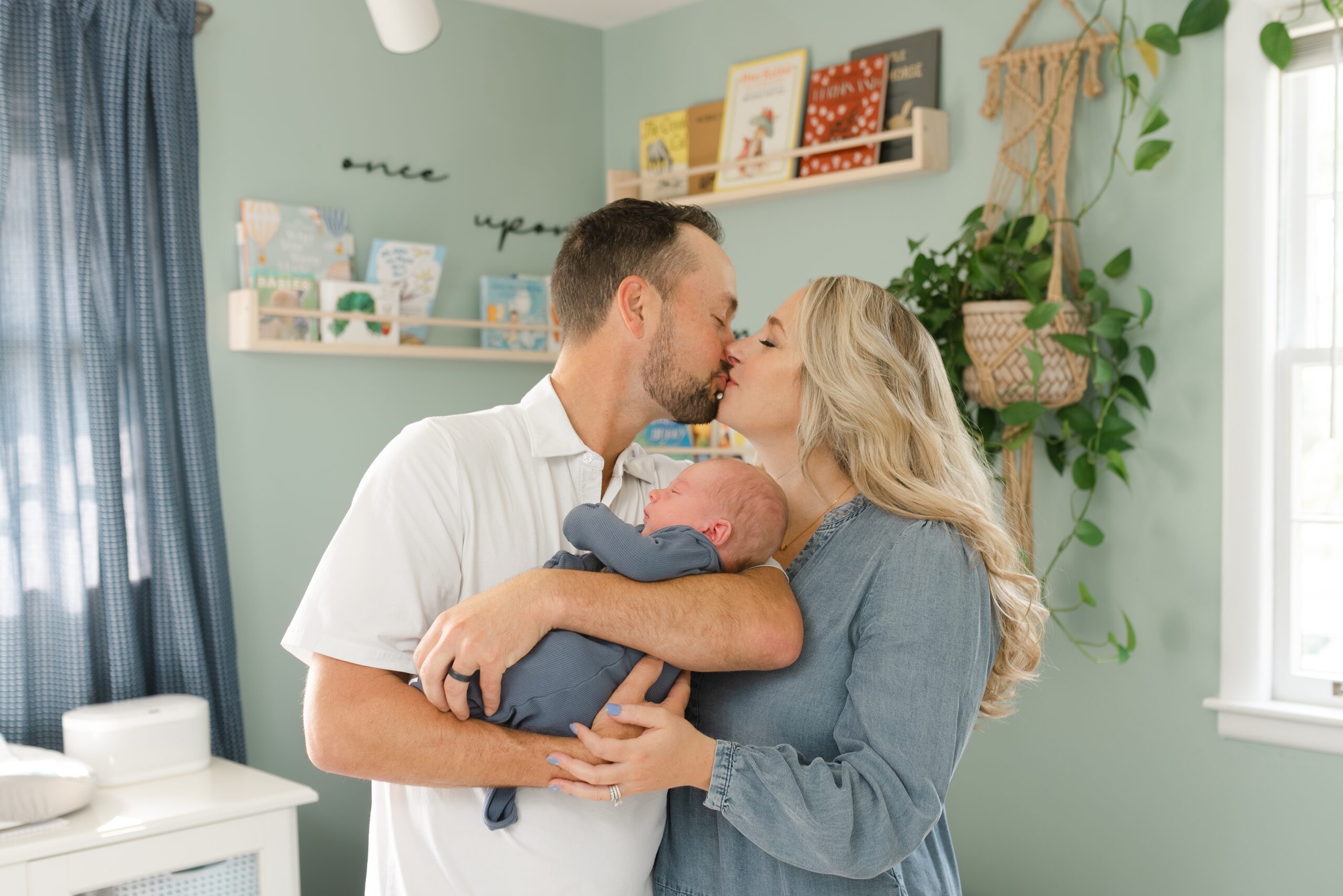 a_mom_and_dad_smile_at_eachother_while_holding_their_newborn_son_at_their_nashville_newborn_photography_Session_With_Dolly_DeLong_Photography