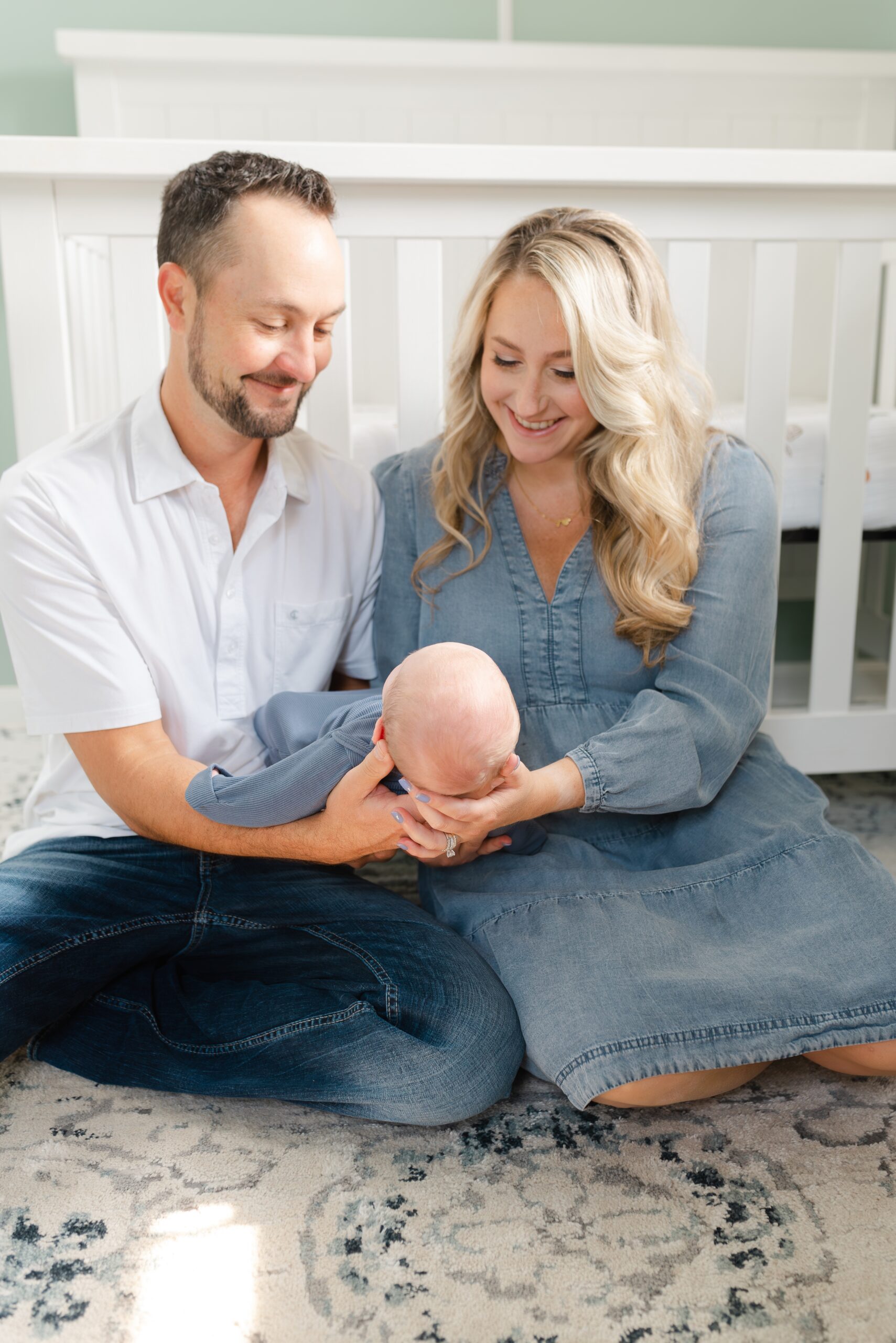 a_mom_and_dad_holding_their_newborn_son_at_their_nashville_newborn_photography_home_session_with_Dolly_DeLong_photography