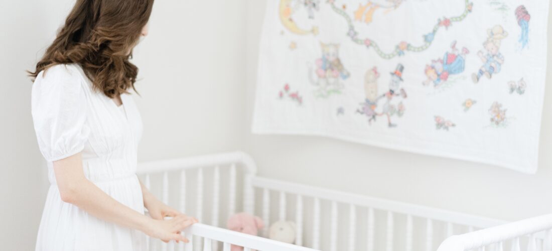an unfocused photo of a mother looking into her newborn daughters crib for her nashville newborn photography session