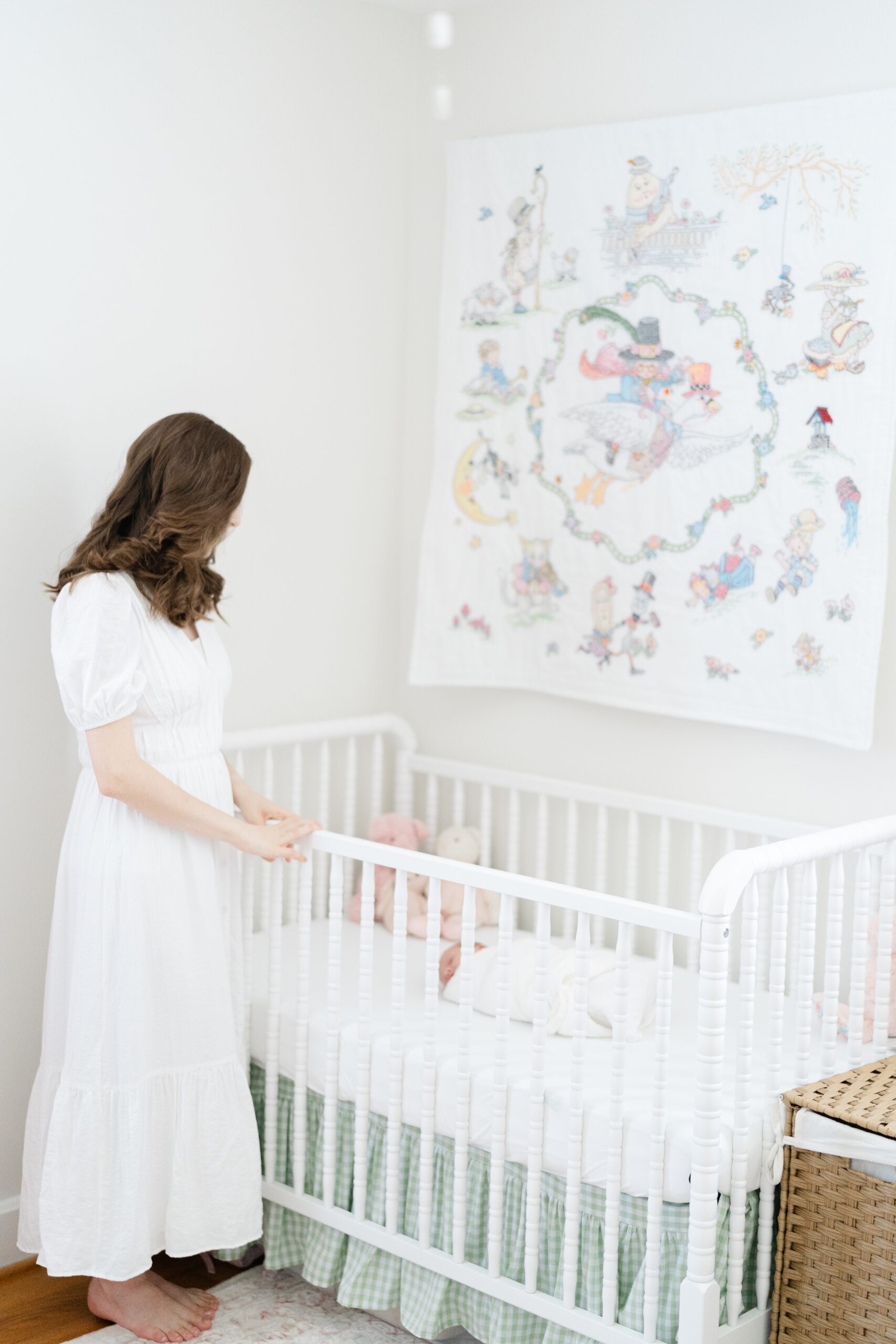an unfocused photo of a mother looking into her newborn daughters crib for her nashville newborn photography session