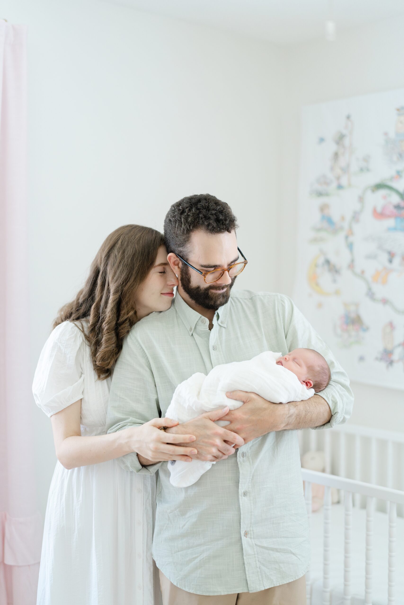 a-mom-and-dad-are-cradling-their-newborn-daughter-and-smiling-down-at-her-for-their-nashville-lifestyle-newborn-photography-session