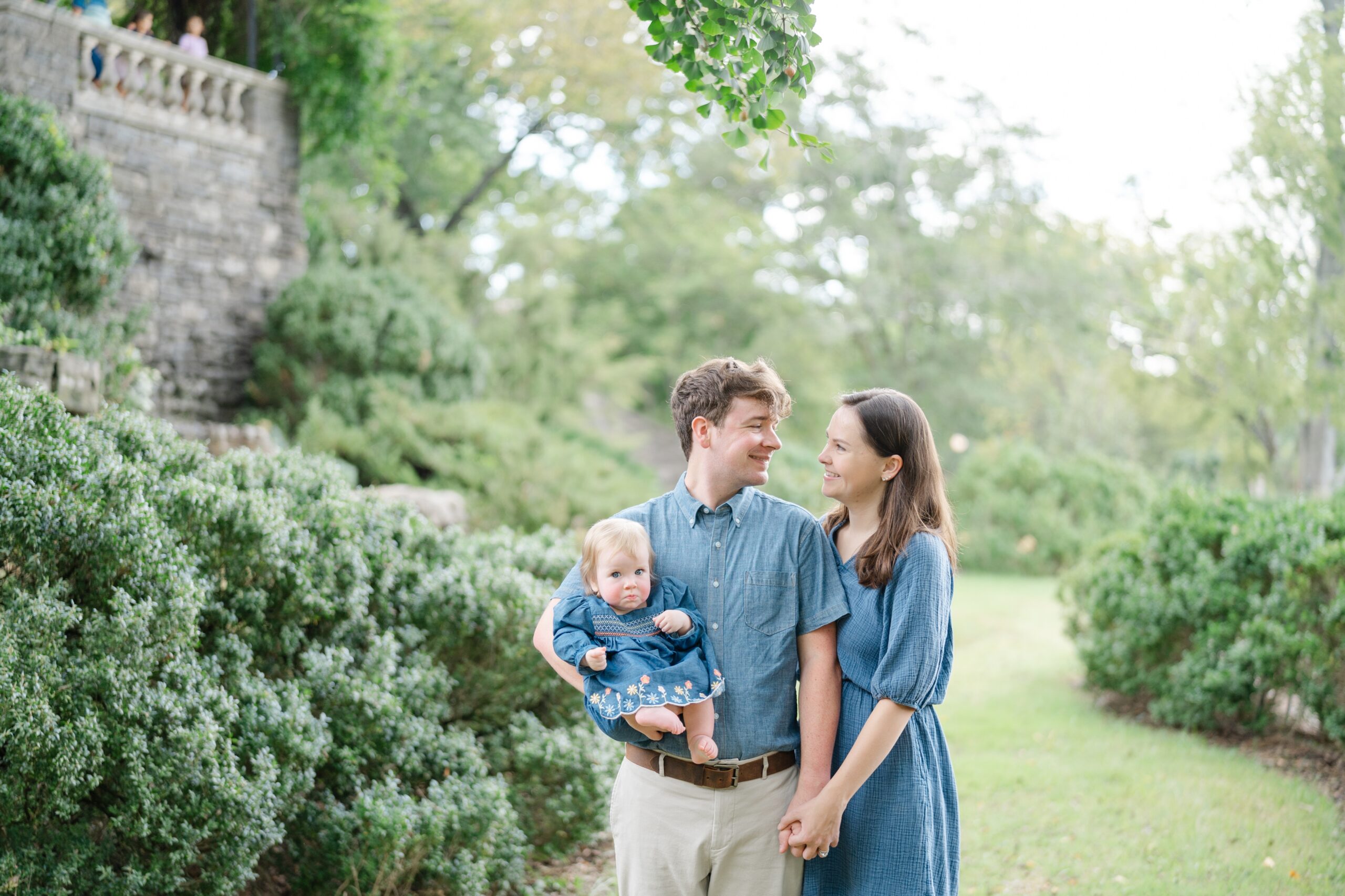 Family of three posing in front of Cheekwood’s lush greenery