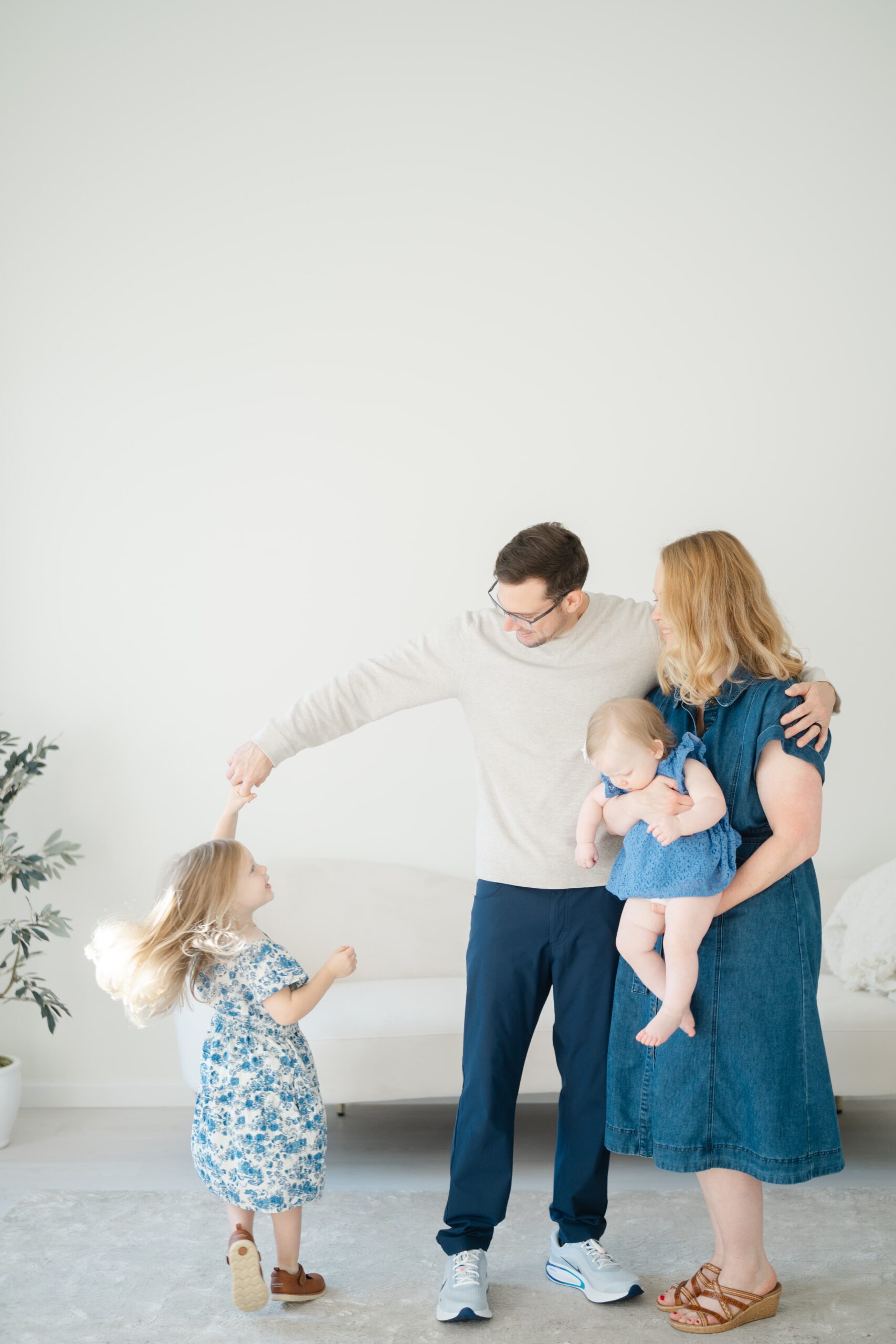 father-spinning-daughter-while-mother-holds-baby-during-a-franklin-tennessee-family-photographer-session