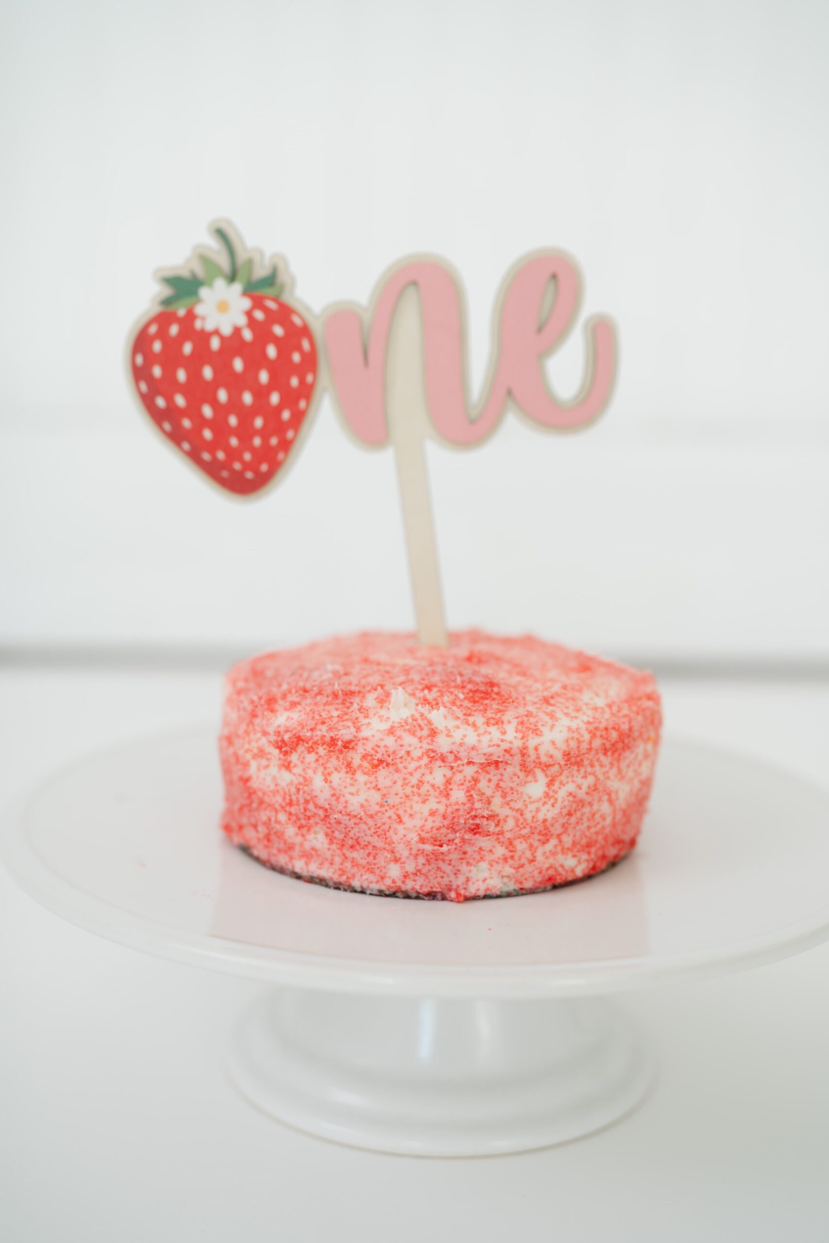 pink-smash-cake-with-strawberry-one-topper-during-cakesmash-session-in-franklin-tennessee