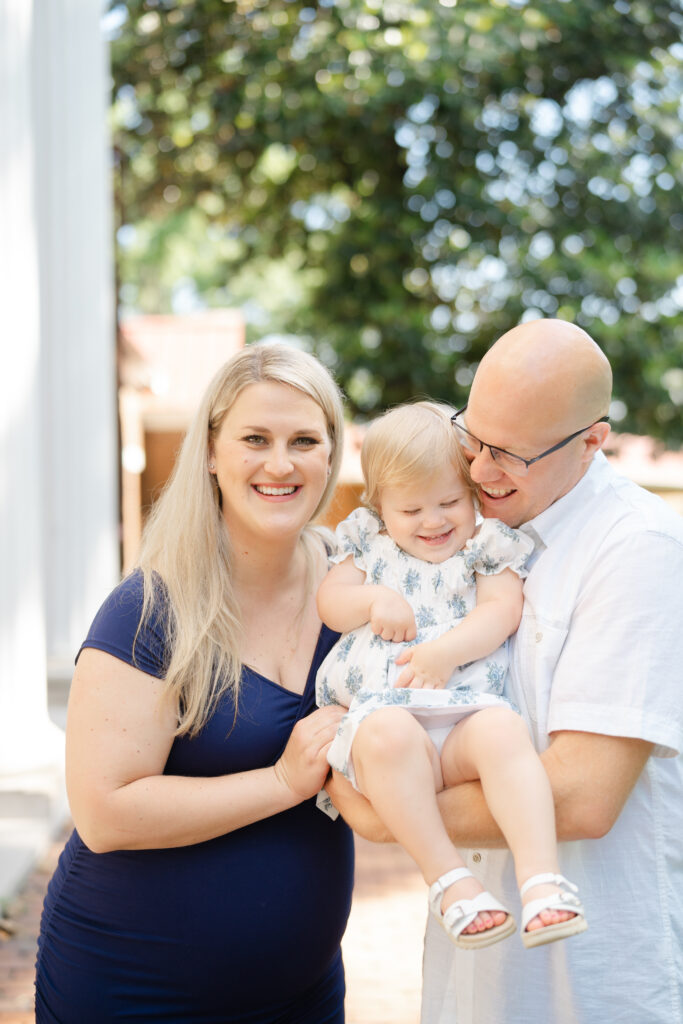 a family of three is snuggling in close together at the nashville ellington ag cultural center for their family session and maternity session